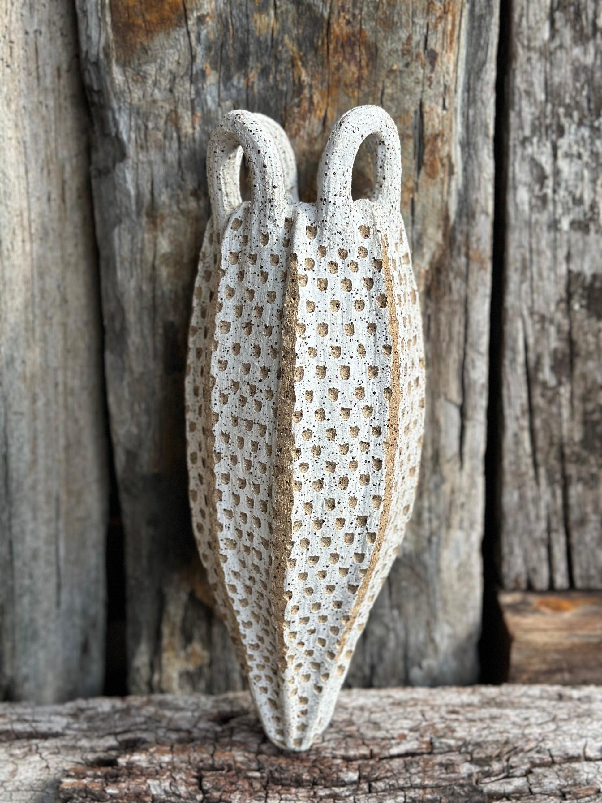 Abstract faceted stoneware form with intricate indents and tapering body, high-fired for rugged tactile finish