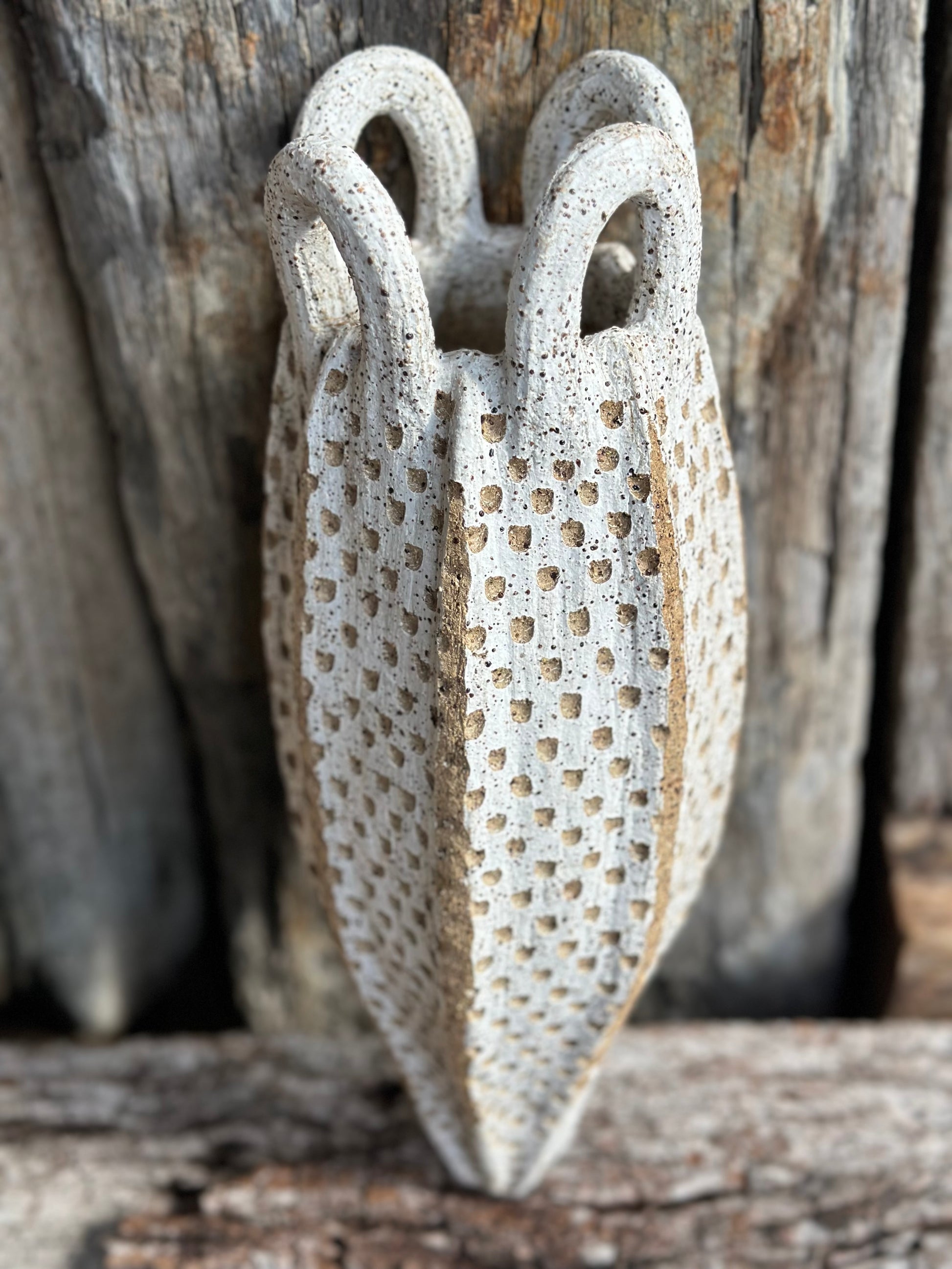 Hand-built stoneware vessel with looped handles and dense carved texture, speckled Australian clay showing white wash.