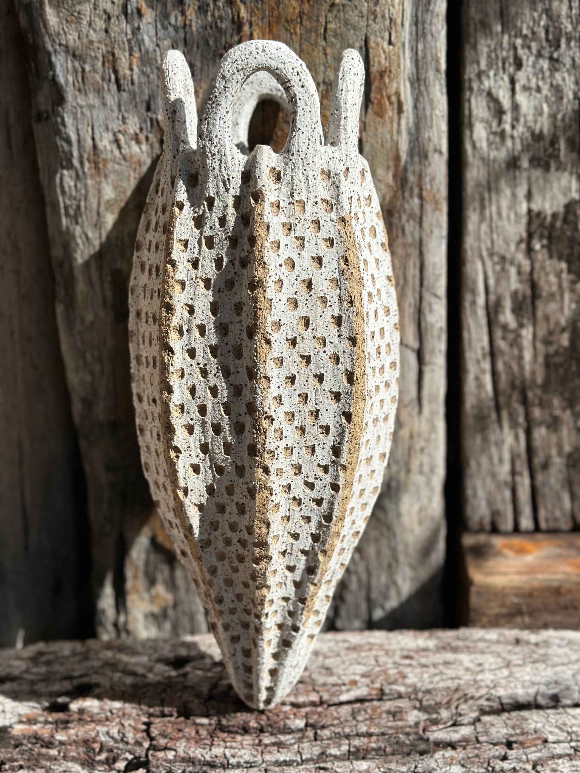 Hand-built stoneware vessel with looped handles and dense carved texture, speckled Australian clay showing white wash.