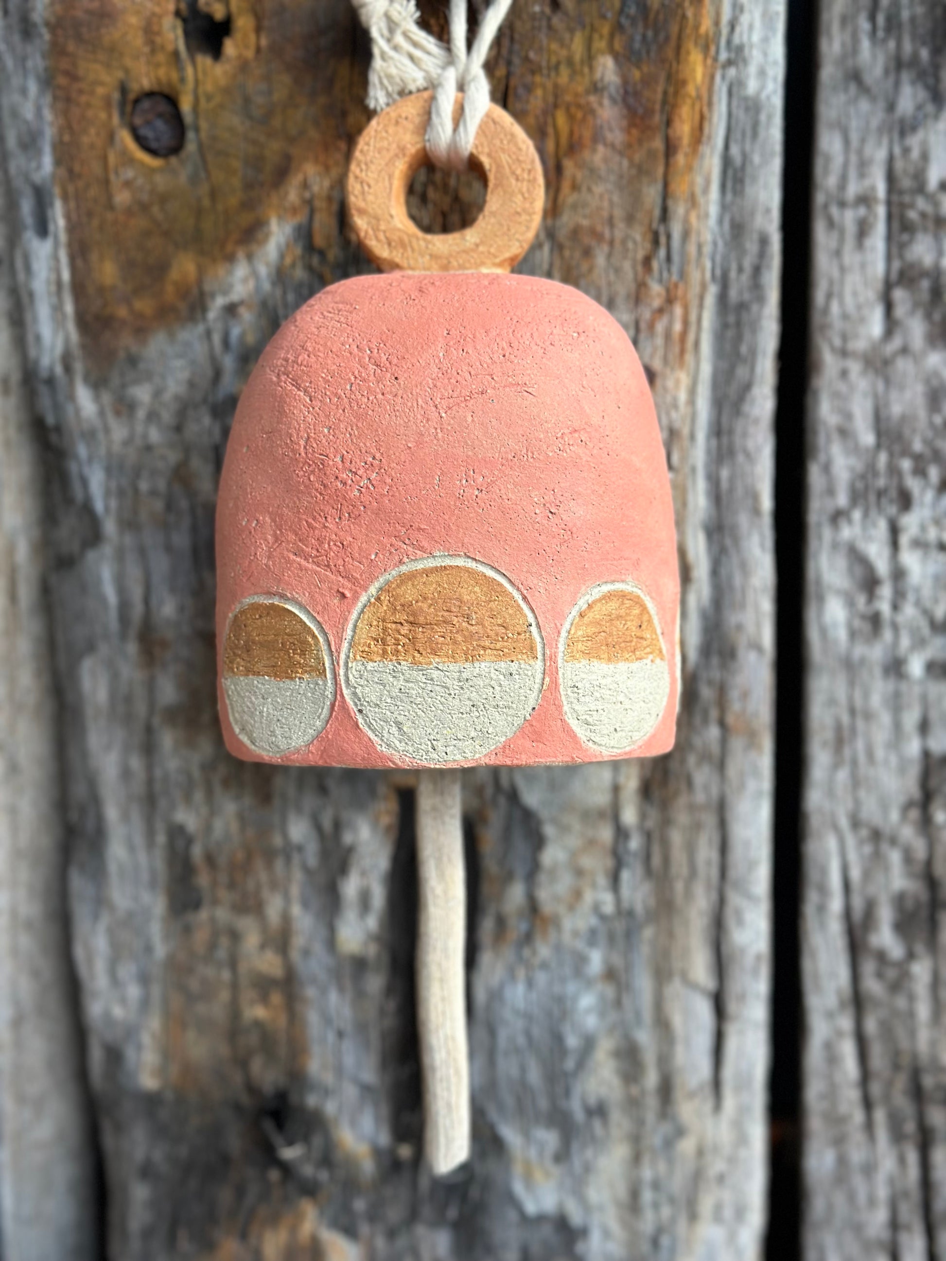 Handcrafted stoneware bell made from textured white raku clay with white circular motif, Danish-inspired design by Heidi Dickinson