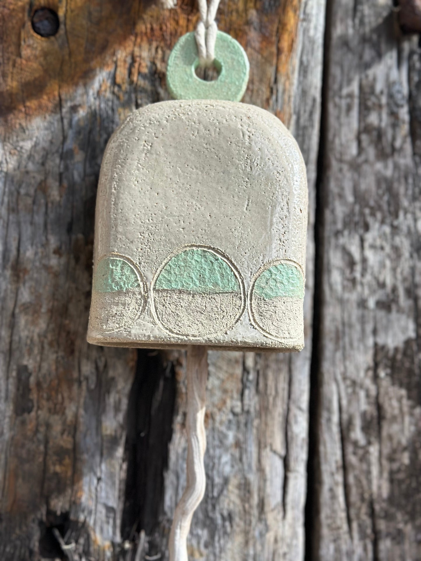 Handcrafted white stoneware bell with mint circular motif, Danish-inspired design by ceramic artist Heidi Dickinson