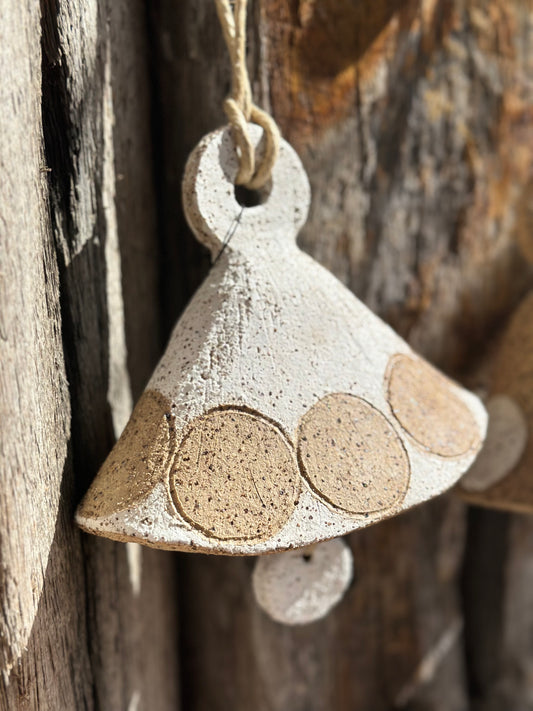 Handmade stoneware bell with gritty whitewashed surface and circular motif, suspended by natural fibre rope