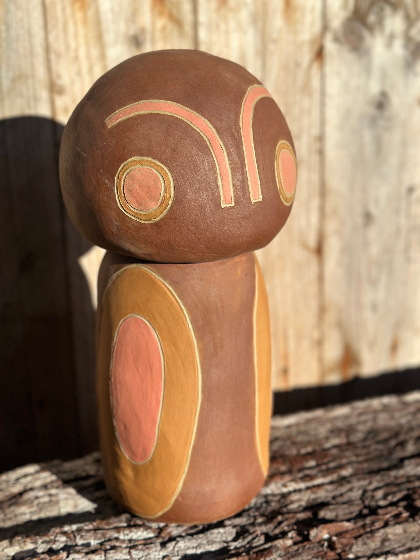 Abstract ceramic figure with minimalist facial features created using sgraffito and inlaid blush and ochre slip on brown stoneware