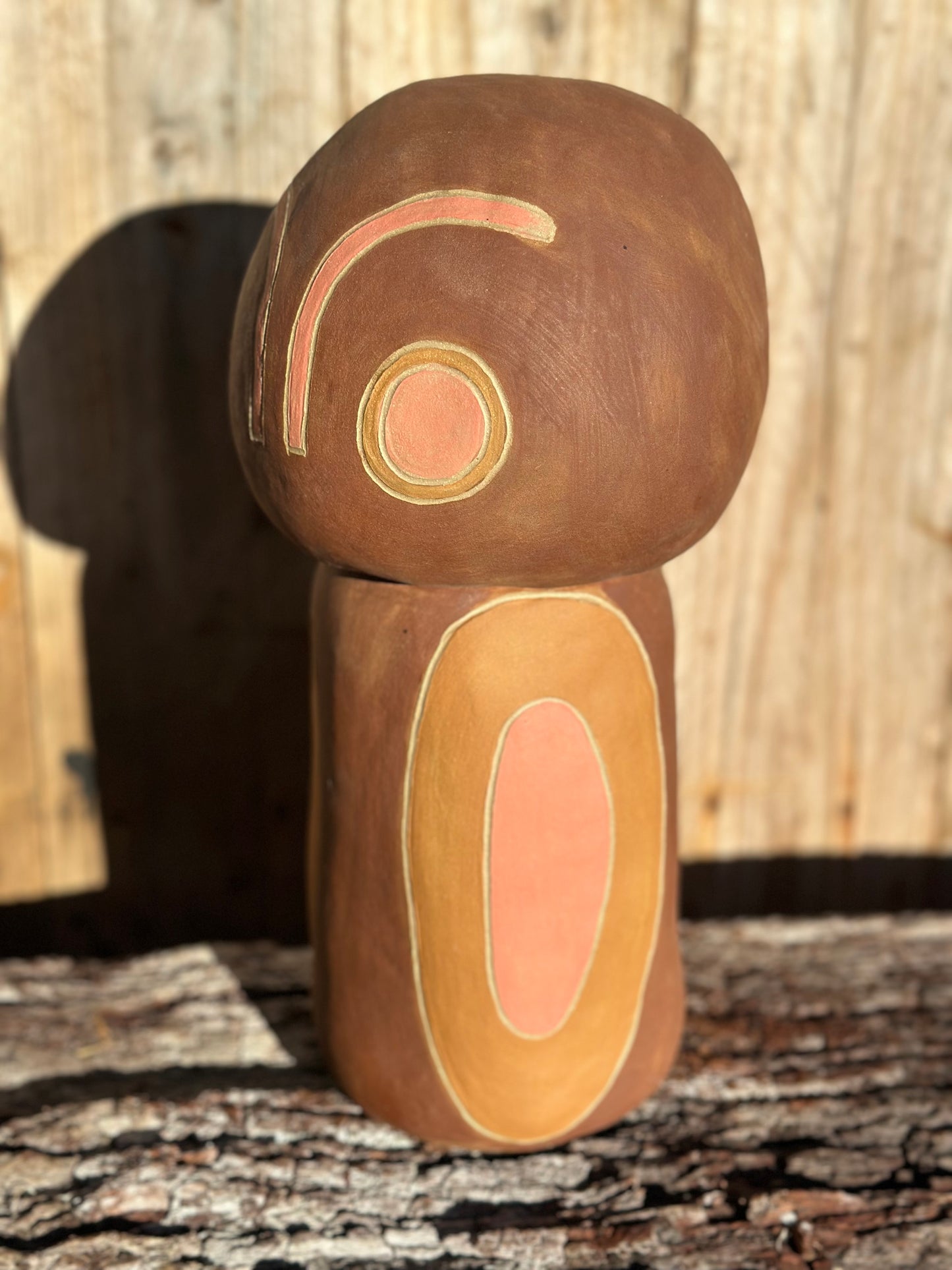 Side view of sculptural ceramic piece with sgraffito surface and warm-toned elliptical motifs