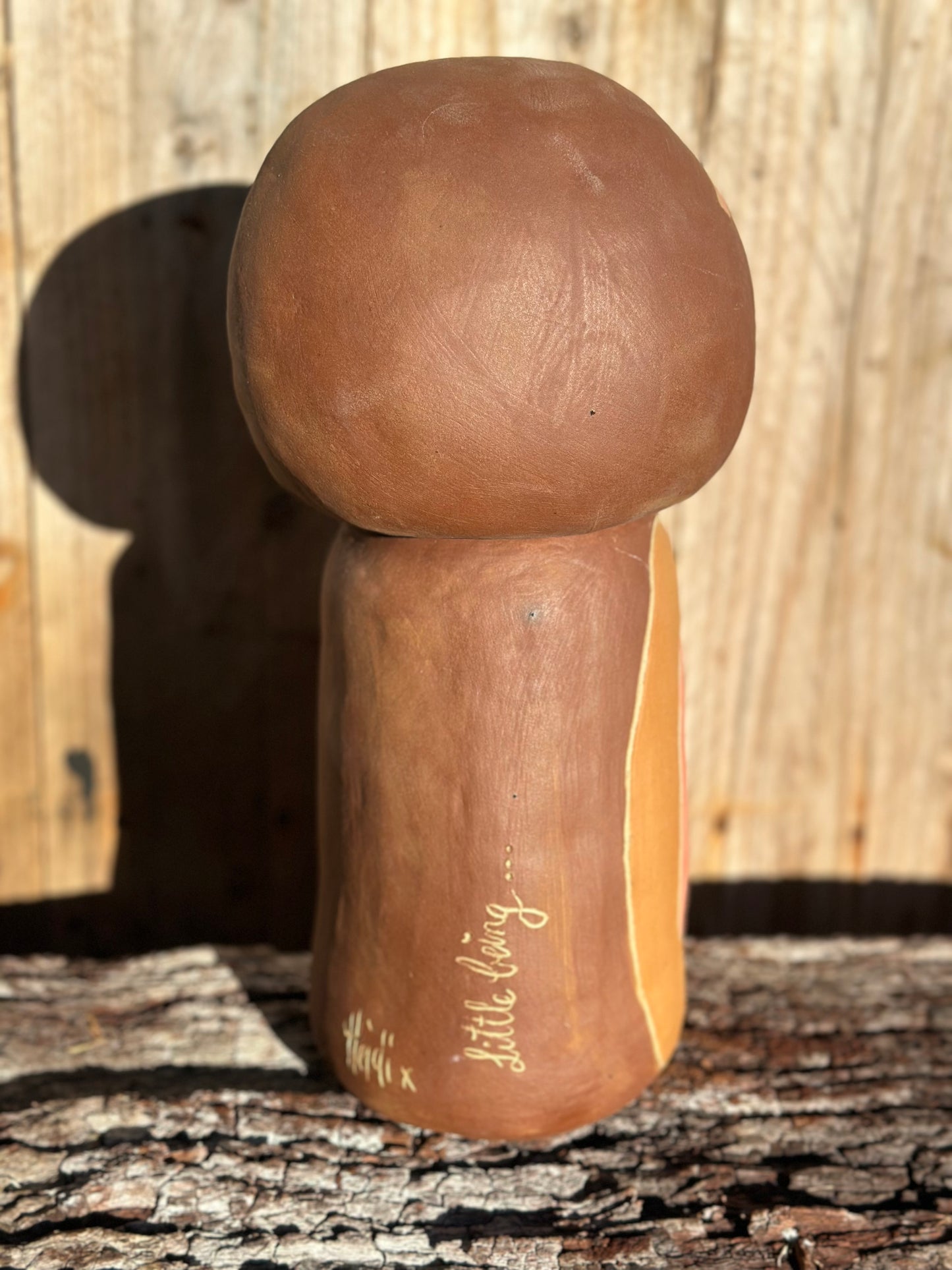 Abstract ceramic figure with minimalist facial features created using sgraffito and inlaid blush and ochre slip on brown stoneware rear view