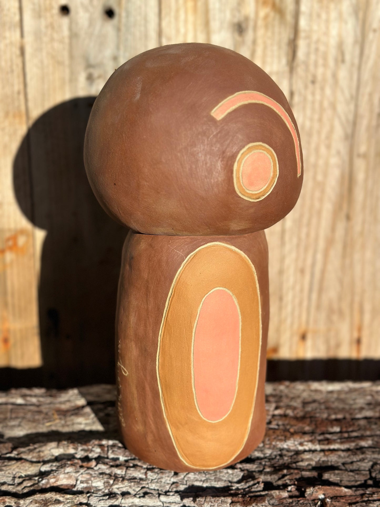 Side view of sculptural ceramic piece with sgraffito surface patterns and warm-toned elliptical motifs