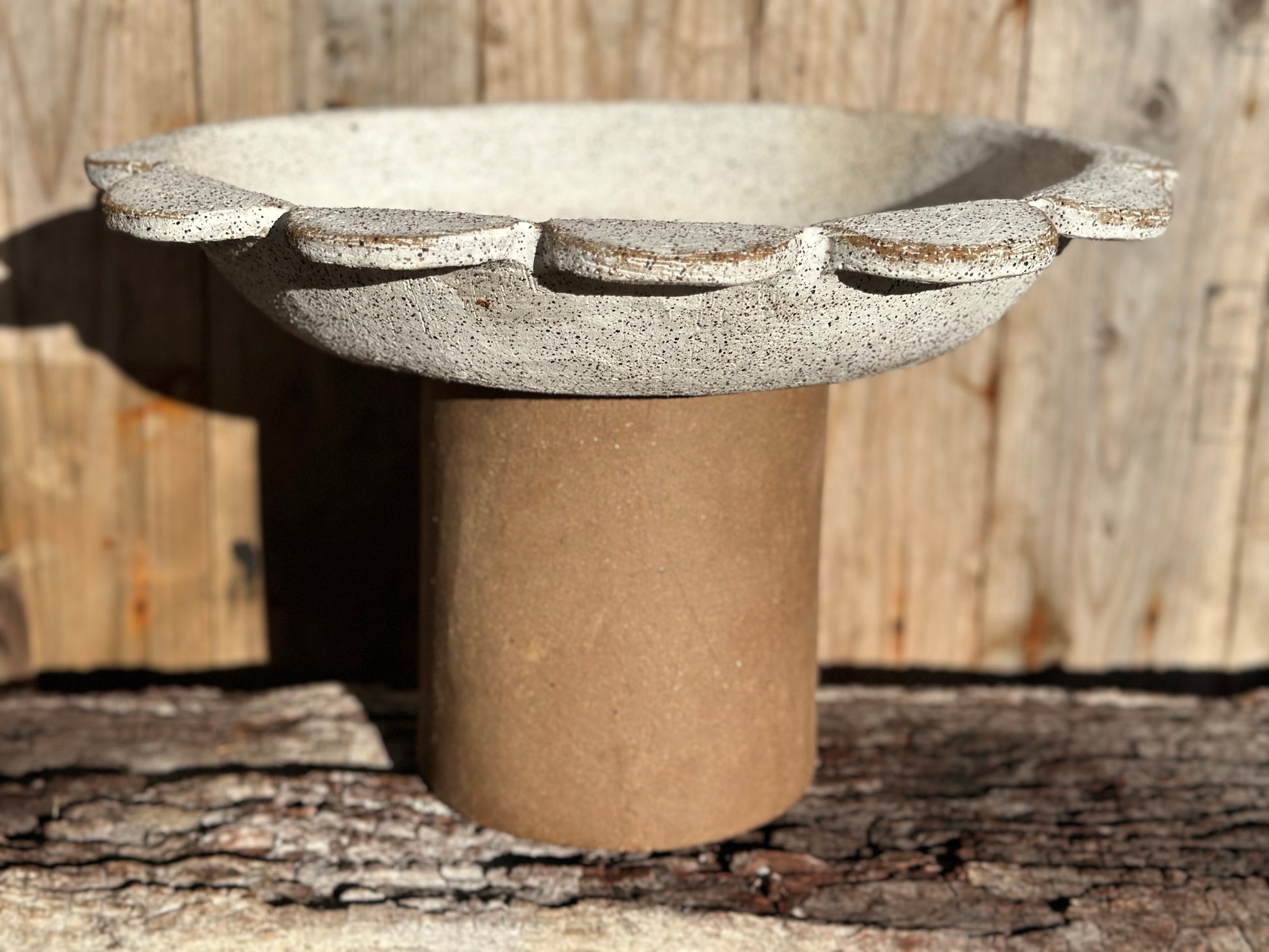 Detailed view Sculptural stoneware vessel with flared, scalloped rim and smooth cylindrical base in contrasting stone ware clay.
