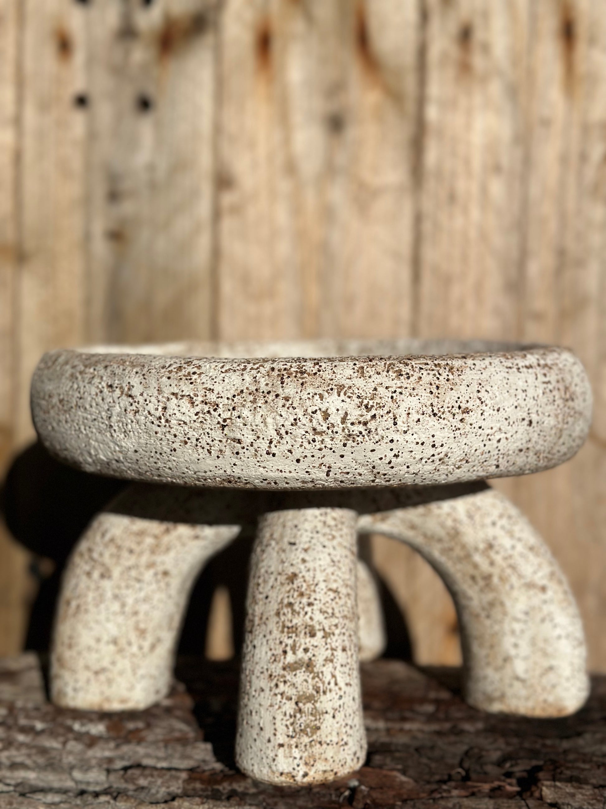 Matte white 2 piece ceramic bowl with softened form and earthy grit exposed along the edge, sitting on curved structural supports